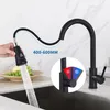 A black kitchen faucet with a pull-down sprayer is shown in use, with water flowing into a sink. A hand is holding the sprayer, which has a digital display. A circular inset shows the hot and cold water controls. Produktbild-Vorschau