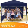 A group of people, including adults and children, are gathered under a blue canopy tent, celebrating what appears to be a birthday with a cake. The scene is outdoors, with grass and trees visible in the background. Produktbild-Vorschau