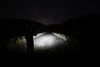 A person stands on a bridge at night, illuminated by a flashlight. Podgląd zdjęcia produktu