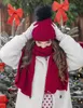 A person wearing a winter hat and scarf in a festive, snowy setting with Christmas decorations. Voir les images du produit