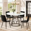 A dining set with a round marble-top table and four black velvet chairs, set in a well-lit room with large windows. Produktbild-Vorschau