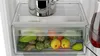 Close-up view of the interior of a refrigerator, showing a crisper drawer filled with fruits and vegetables, and a pot on the shelf above. Produktbild-Vorschau