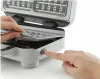A close-up shot of hands interacting with a waffle maker. Produktbild-Vorschau