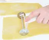 A hand is using a pasta cutter to cut a sheet of pasta dough. Náhľad obrázku produktu