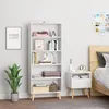 A white bookshelf filled with books and decorative items, next to a nightstand and a bed. A plant is placed on the floor. Náhľad obrázku produktu