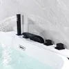 A black bathtub faucet with a handheld showerhead is installed on the edge of a white bathtub filled with clear water. Produktbild-Vorschau