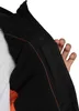 A close-up view of the inside of a black jacket with orange lining, showing a hand reaching into a pocket. Produktbild-Vorschau