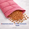A close-up of a red and white checkered fabric pouch spilling out dried beans or seeds onto a textured white surface. Produktbild-Vorschau