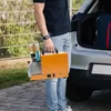 A person is holding a portable air compressor next to the open trunk of a car. Produktbild-Vorschau