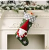 A Christmas stocking with a gnome decoration hangs on a fireplace mantel. Náhľad obrázku produktu