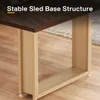 Close-up of the base structure of a wooden dining table, highlighting its sled base and metal frame. Anteprima dell’immagine prodotto