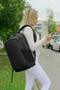 A woman wearing a backpack and looking at her phone. Produktbild-Vorschau