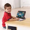A young boy is sitting at a wooden table and playing with a toy laptop. Produktbild-Vorschau