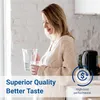 A woman is holding a water pitcher and a glass in a kitchen. Produktbild-Vorschau