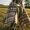 A couple walks in a grassy field, sharing a plaid blanket. Náhled obrázku produktu
