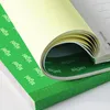 A close-up of a green notepad with pages being unrolled, revealing text on the pages. Podgląd zdjęcia produktu