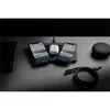 A black wireless charging pad with two iPhones and a pair of white earbuds charging on it, along with a black charging cable and a small black speaker on a dark desk. Voir les images du produit