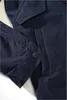 A close-up view of a navy blue jacket, showing a button and pocket detail. Náhled obrázku produktu