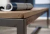 Close-up of a wooden tabletop with a metal frame, and a rolled-up magazine on top. Anteprima dell’immagine prodotto