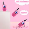 Multiple pink walkie-talkies are displayed against a pink background, with text overlays highlighting features like 'Fall Resistant' and 'ABS+PC'. One walkie-talkie is shown on a white pedestal, another is angled, and a third is depicted on a cracked surfa Podgląd zdjęcia produktu