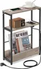 A narrow side table with three shelves, featuring a built-in charging station and a magazine rack. It is shown with a smartphone, a vintage-style radio, a cup and saucer, and magazines. Produktbild-Vorschau