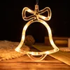 A close-up shot of a bell-shaped LED light decoration hanging against a dark background, with some decorative items in the foreground and background. Produktbild-Vorschau