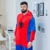 A man wearing a Spiderman onesie stands in a room with framed pictures on the wall and a desk with a typewriter. Anteprima dell’immagine prodotto