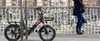 A person stands on a bridge next to an electric bicycle. Produktbild-Vorschau