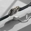 A smartwatch and its charger are placed on a textured surface with shadows. Náhled obrázku produktu