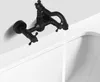 A black wall-mounted faucet with water running into a white sink. Produktbild-Vorschau