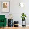 A modern living room scene with a green sofa, a decorative pedestal, a stool, and a plant stand. Podgląd zdjęcia produktu