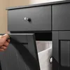 A hand is opening a cabinet door to reveal a laundry basket inside. Podgląd zdjęcia produktu