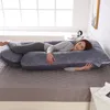 A woman is sleeping on a large U-shaped pregnancy pillow in a bedroom. Náhled obrázku produktu
