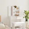 A white vanity table with a mirror and shelves filled with cosmetics, placed in a room with a bed and a plant. Náhled obrázku produktu