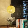 A hanging lamp with a woven shade is shown above a table with books and flowers. Anteprima dell’immagine prodotto