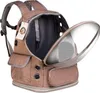 A brown pet carrier backpack with a clear bubble window is shown from the front, with the main compartment partially open. Náhľad obrázku produktu
