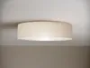 A round ceiling light with a fabric shade is mounted on a white ceiling. Produktbild-Vorschau