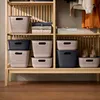 Storage baskets are neatly arranged on wooden shelves in a closet. Produktbild-Vorschau