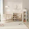 A nursery room with a crib, clothing rack, and bookshelf. Anteprima dell’immagine prodotto