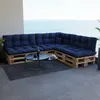 A sectional sofa made of wooden pallets with dark blue cushions sits on a balcony overlooking the ocean. Anteprima dell’immagine prodotto