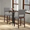 A set of two bar stools and a small round table are placed near a window with a city view. Produktbild-Vorschau