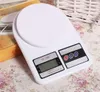 A white digital kitchen scale on a floral patterned surface, with a yellow box partially visible. Voir les images du produit