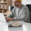 A man wearing a yellow beanie and glasses is working on a laptop, with a smartphone with a ring holder in the foreground. Podgląd zdjęcia produktu