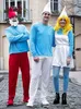 Three people dressed in Smurf costumes posing for a photo on a cobblestone street. Produktbild-Vorschau