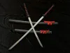 Two katanas are crossed over two scabbards on a black fabric background. Voir les images du produit