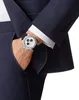 A man's hand wearing a watch, with his arm inside a navy blue suit jacket. Produktbild-Vorschau