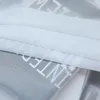 A close-up view of a white, semi-transparent fabric with large white lettering on it, layered over a gray surface with smaller text. Produktbild-Vorschau