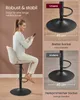 A woman is sitting on a bar stool, looking at her phone. The image also shows close-ups of the stool's base with dimensions and comparison text. Produktbild-Vorschau