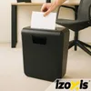 A hand is feeding a piece of paper into a black paper shredder in an office setting. Produktbild-Vorschau