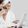 A woman is applying makeup to a young girl in front of a mirror. Produktbild-Vorschau